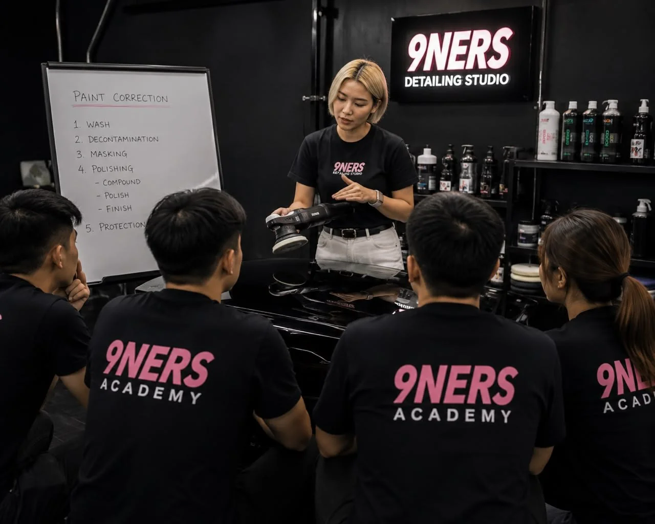 Nina teaching a paint correction class to students in 9NERS Academy shirts